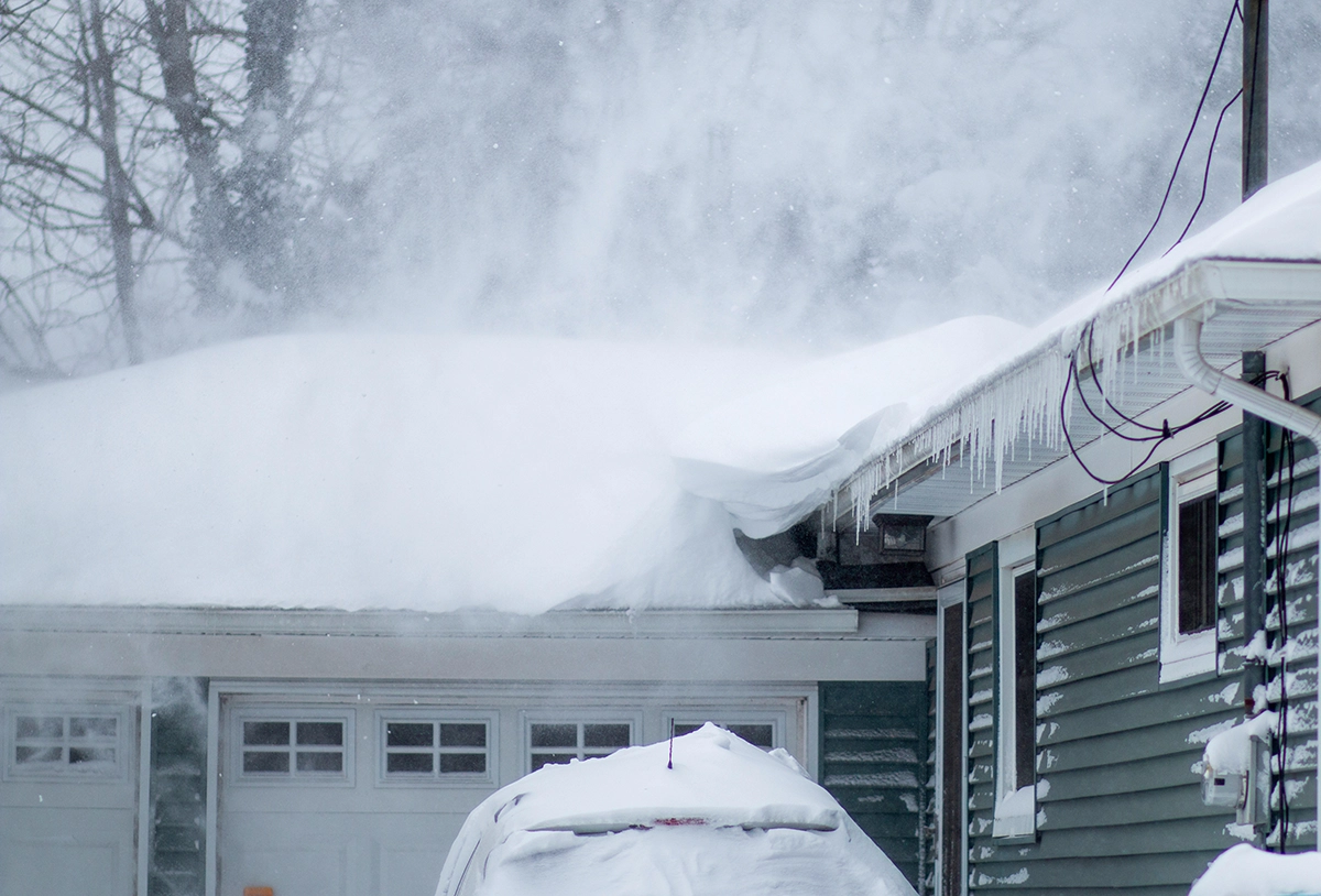 Residential home covered in heavy snow with roof snow buildup during winter storm
